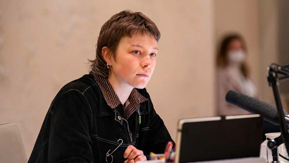 Emma D'Arcy in a black sweater and short hair looking away during a table read