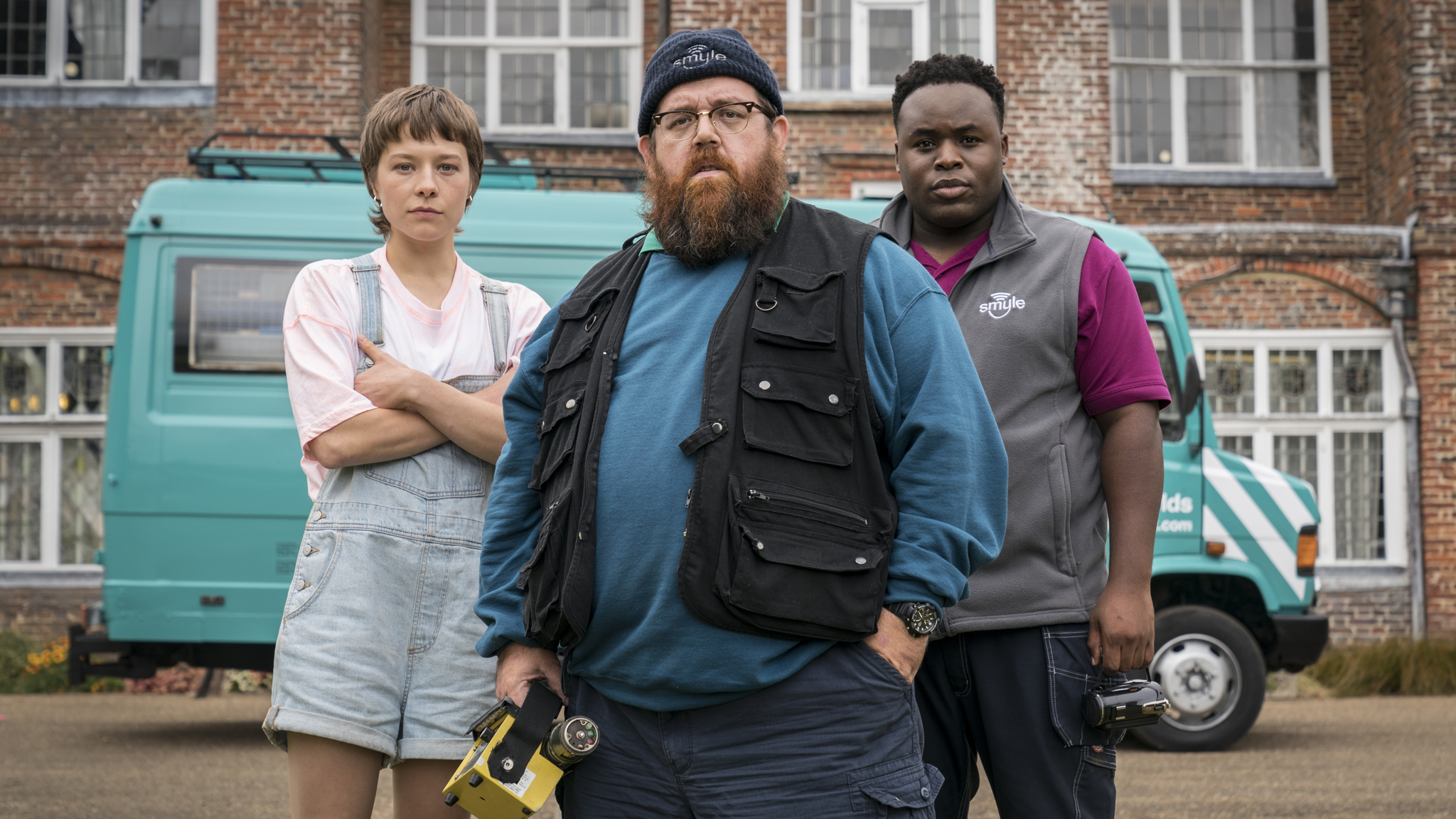 Nick Frost wearing a blue tee and jacket and Emma D'Arcy in overalls in a still from truth Seekers