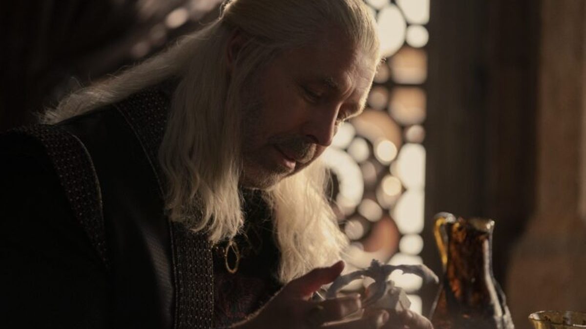 King Viserys with a stone model of a dragon.